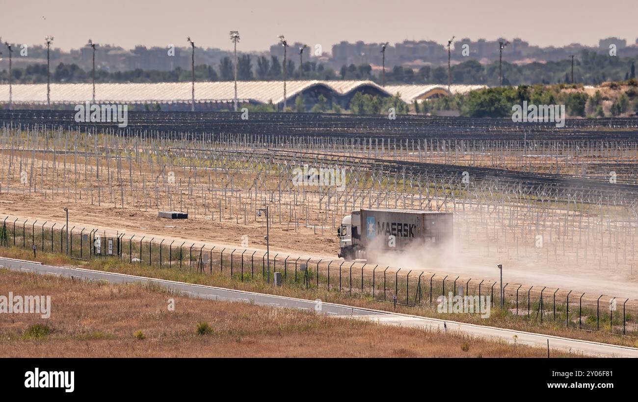 Madrid, Spagna; 05-24-2024: Camion con un container dell'azienda logistica Maersk che si muove rapidamente su una strada sterrata sollevando una grande nuvola di polvere Foto Stock