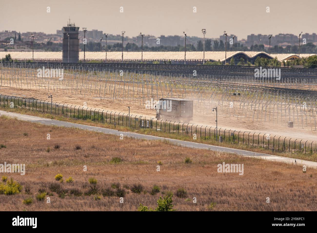 Madrid, Spagna; 05-24-2024: Camion con un container dell'azienda logistica Maersk che si muove rapidamente su una strada sterrata sollevando una grande nuvola di polvere Foto Stock
