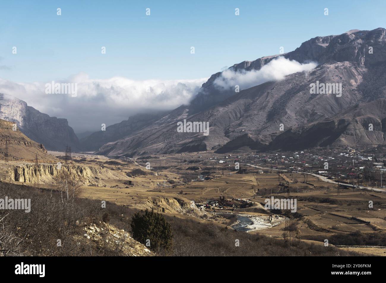 Una vista del villaggio di montagna nella gola nel Caucaso. Picchi grigi di montagne con nuvole e gole con case e insediamenti Foto Stock