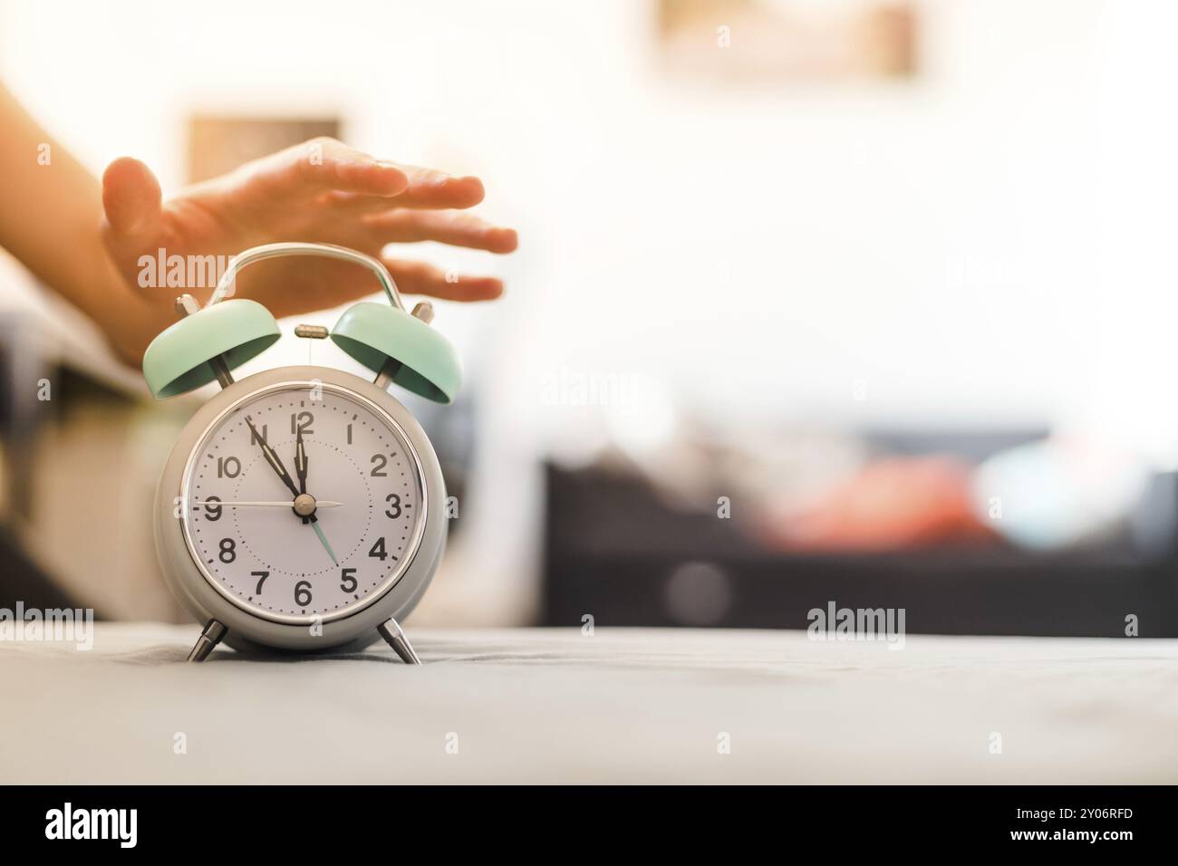 L'uomo sta spingendo una sveglia, il sole al mattino, sfondo sfocato Foto Stock