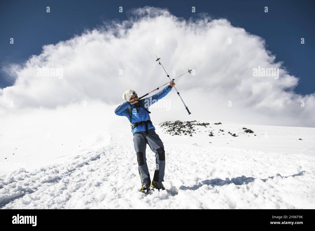 Backpacker in montagna finge di sparare un arco usando l'esempio dei bastoni per camminare scandinavo sullo sfondo di un imminente st Foto Stock