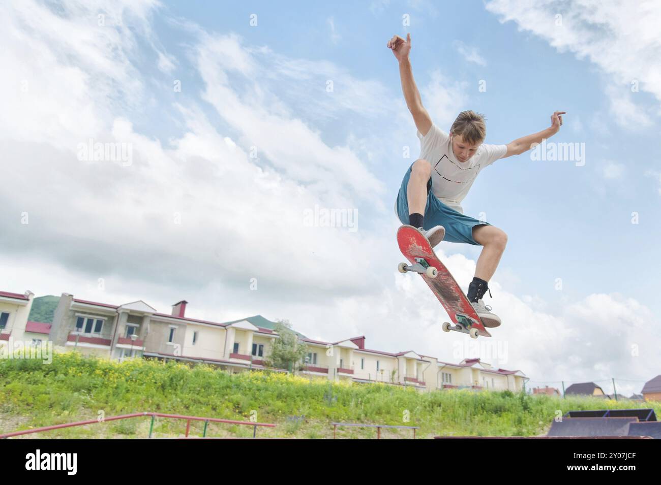 Giovane e intenso skateboarder in salto in alto contro il cielo e le zone notte Foto Stock