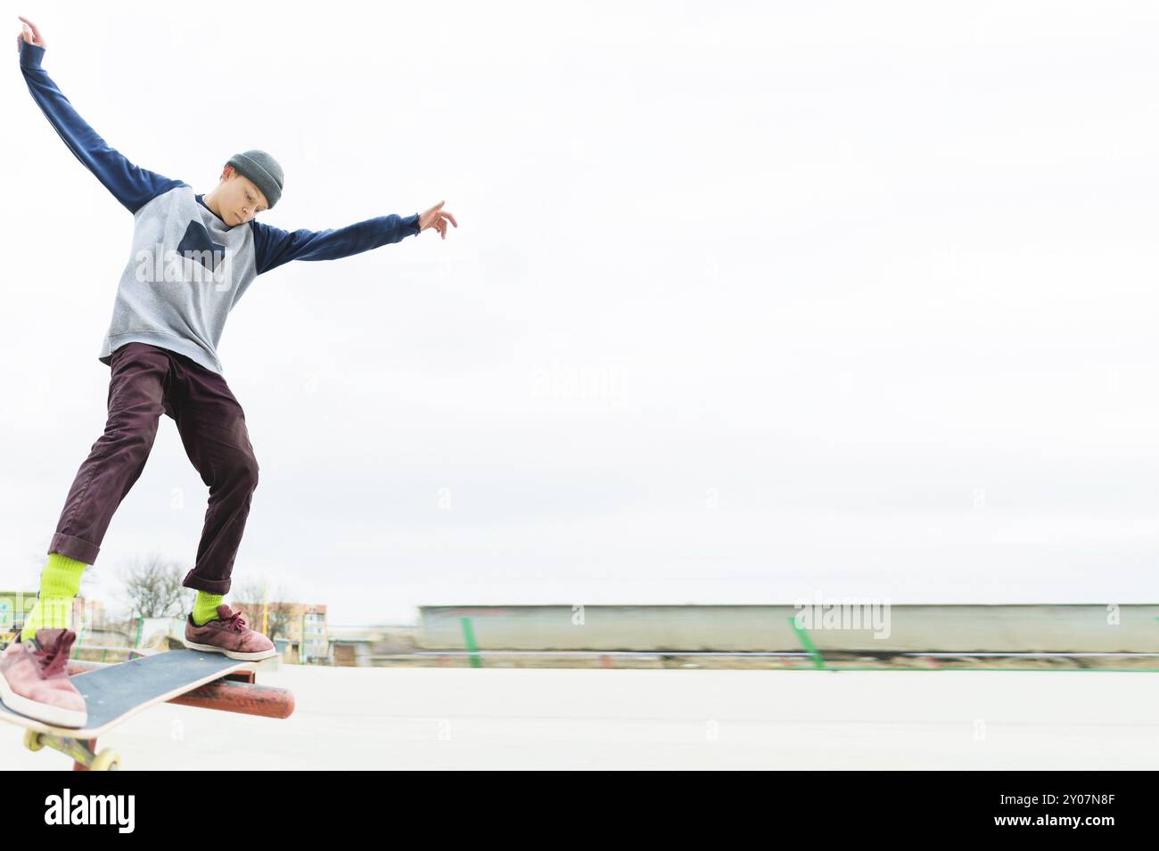 Un giovane adolescente, uno skateboarder, fa un trucco sulla ringhiera in uno skatepark. Il concetto di sport giovanili nella cultura urbana Foto Stock