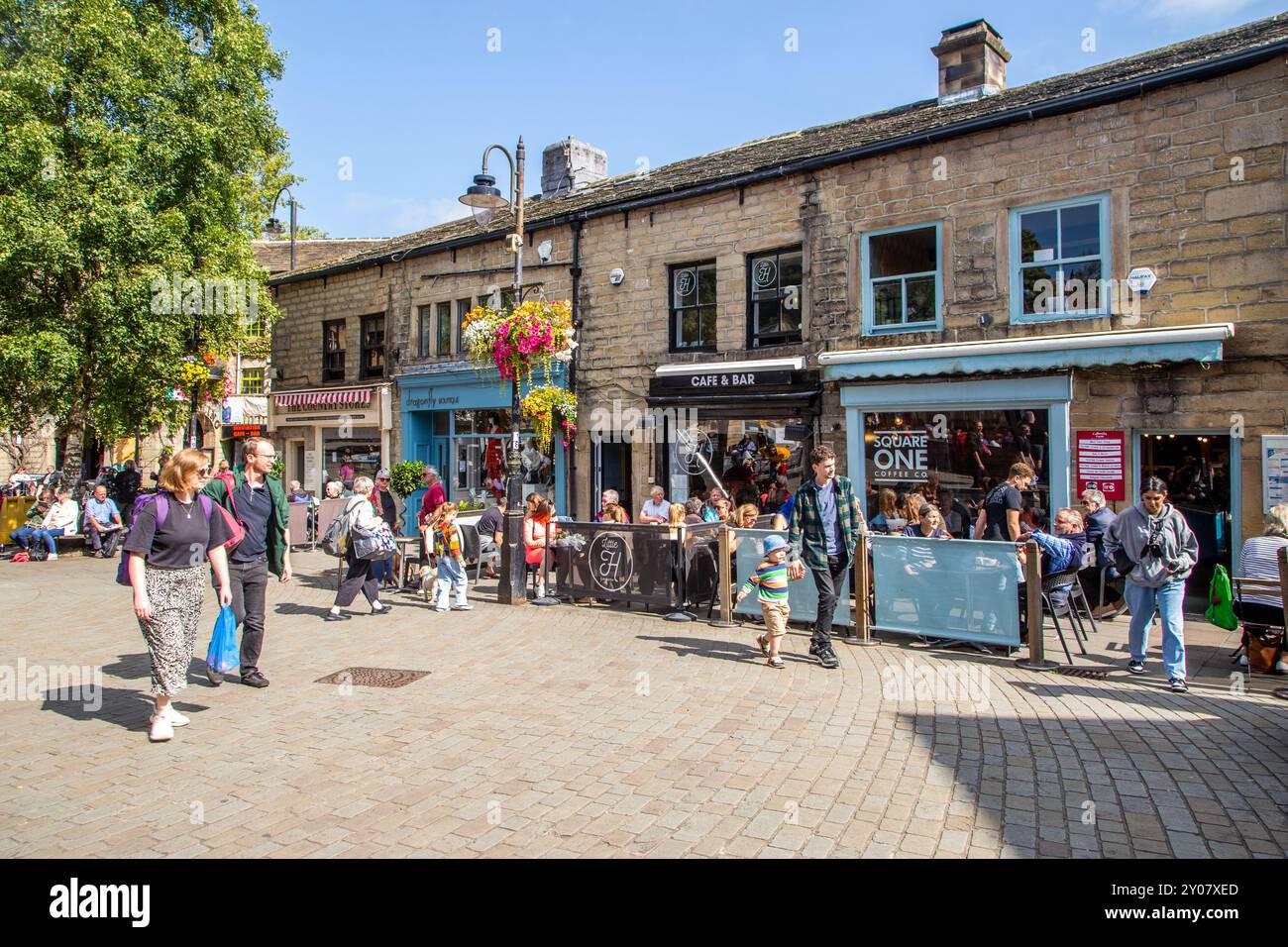 Gente di St George's Square, nella città di Hebden Bridge, nel West Yorkshire, che gode del sole estivo, mangiando e bevendo all'aperto Foto Stock