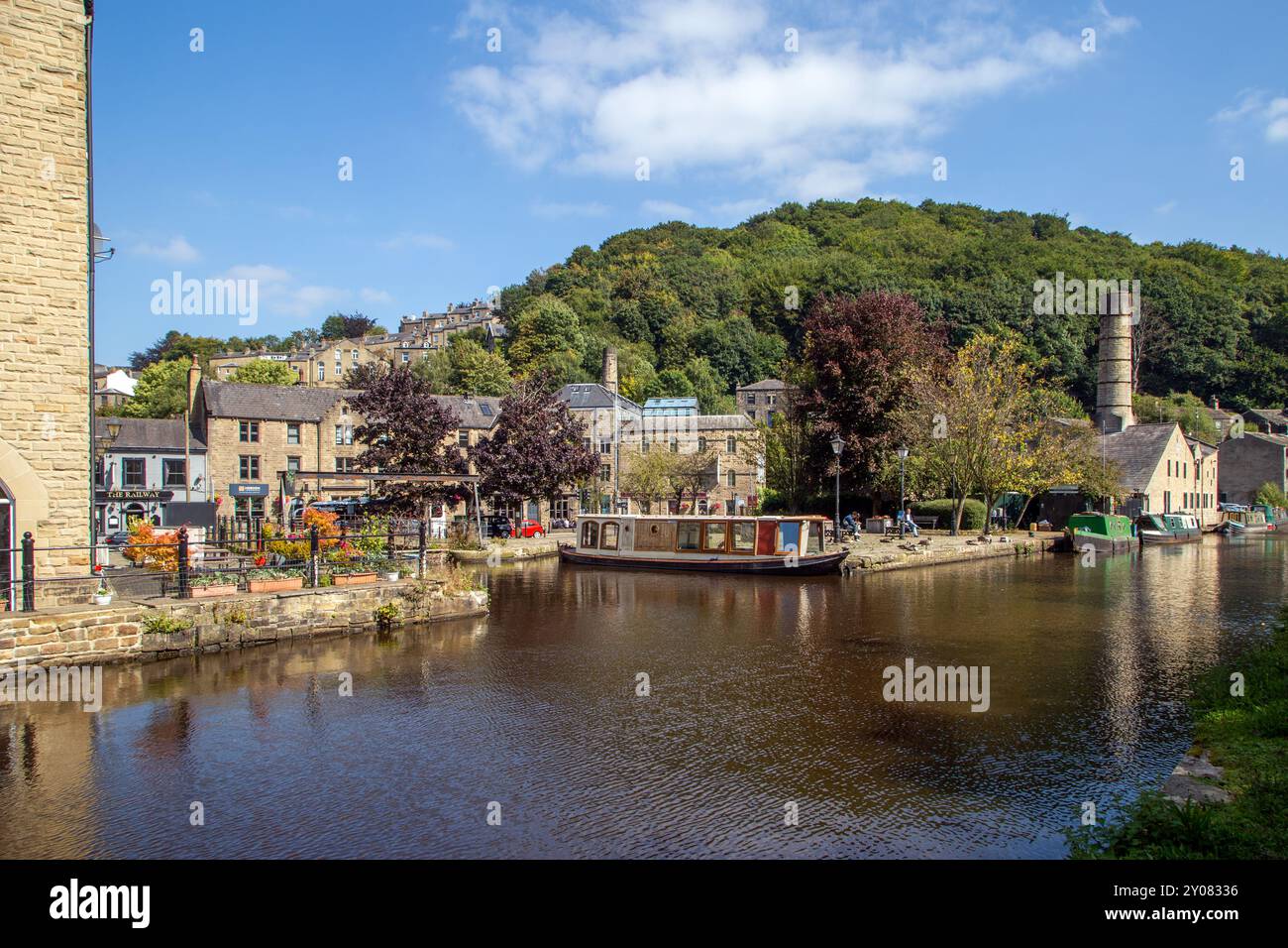 La barca stretta del canale è ormeggiata lungo gli ex edifici del pontile sul canale di Rochdale nella Calder Valley, città mercato dello Yorkshire occidentale, di Hebden Bridge Foto Stock