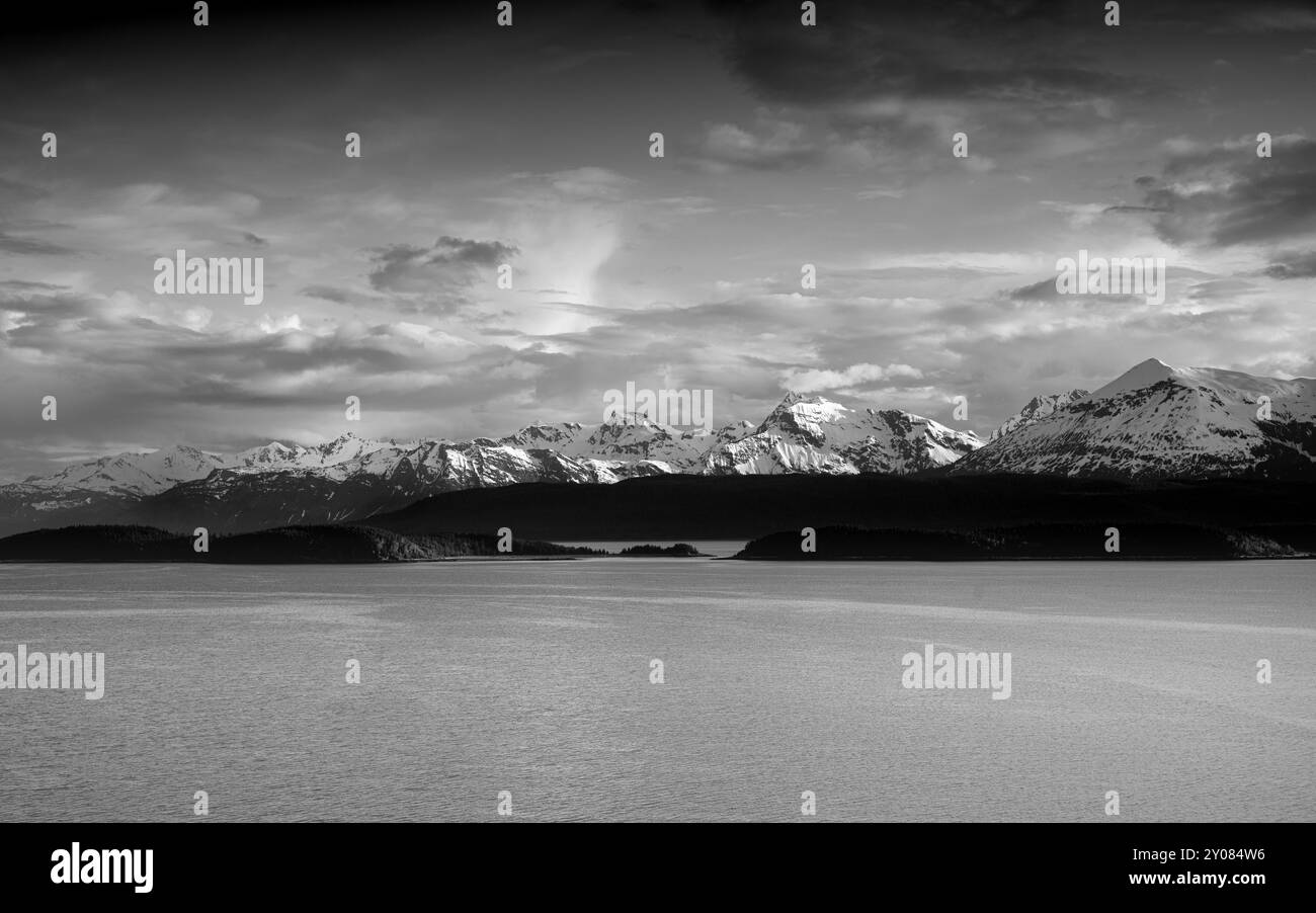 il paesaggio marino con la linea di alberi sagomati contro la catena montuosa innevata cieli spettacolari. Alaska, stati uniti, Foto Stock