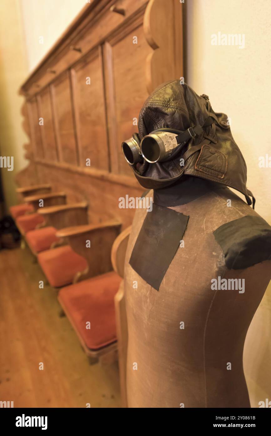 Il manichino di un vecchio sarto con casco in pelle e occhiali si staglia davanti a pedine vuote Foto Stock Il manichino di un vecchio sarto con casco in pelle e occhiali si staglia davanti a pedine vuote Foto Stock