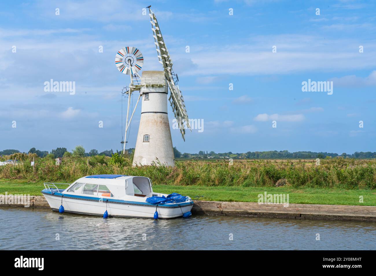 Thurne Drainage Mill sul Norfolk Broads National Park nel Regno Unito con una barca in primo piano in una giornata estiva orientata al paesaggio Foto Stock