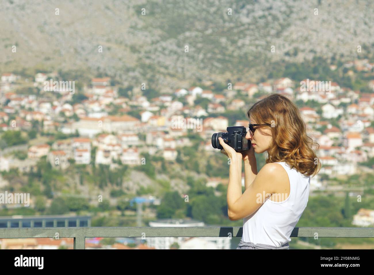 Una blogger donna scatta una foto della vista della città di Trebinje mentre si trova al punto di osservazione del monastero di Hercegovacka Gracanica Foto Stock