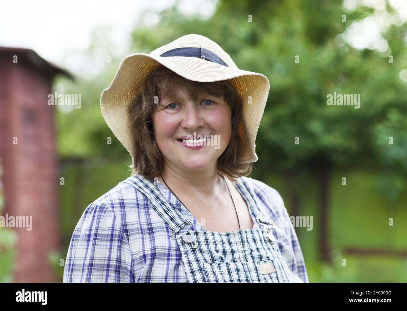 Donna di mezza età in cappello che lavora in giardino Foto Stock