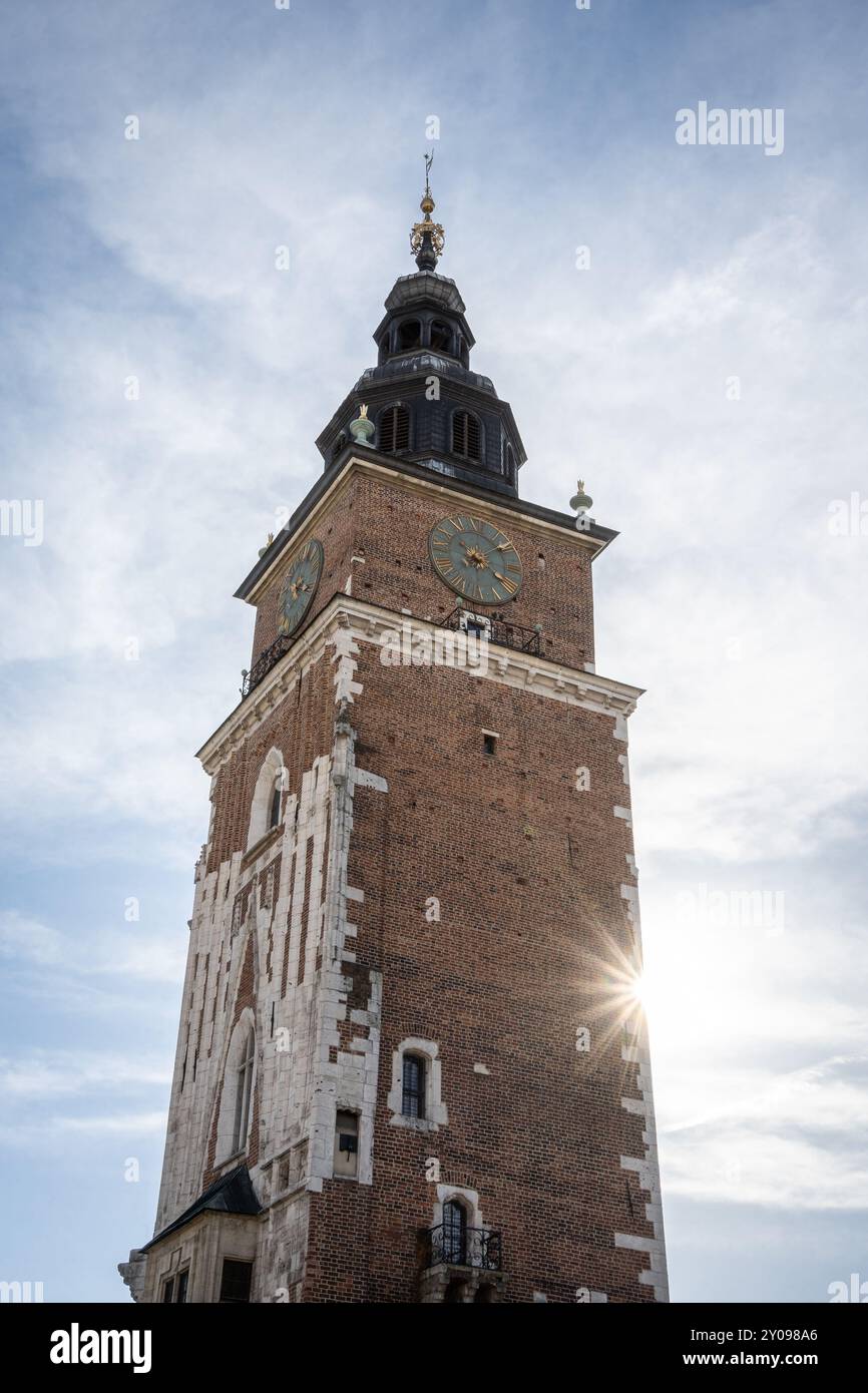 Scatto verticale di una torre storica con orologio e sole che tramonta dietro di essa, Cracovia, Polonia Foto Stock