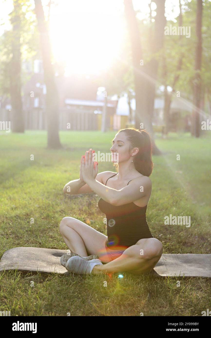 Giovane donna meditando all'aperto in estate Sunset Park Foto Stock