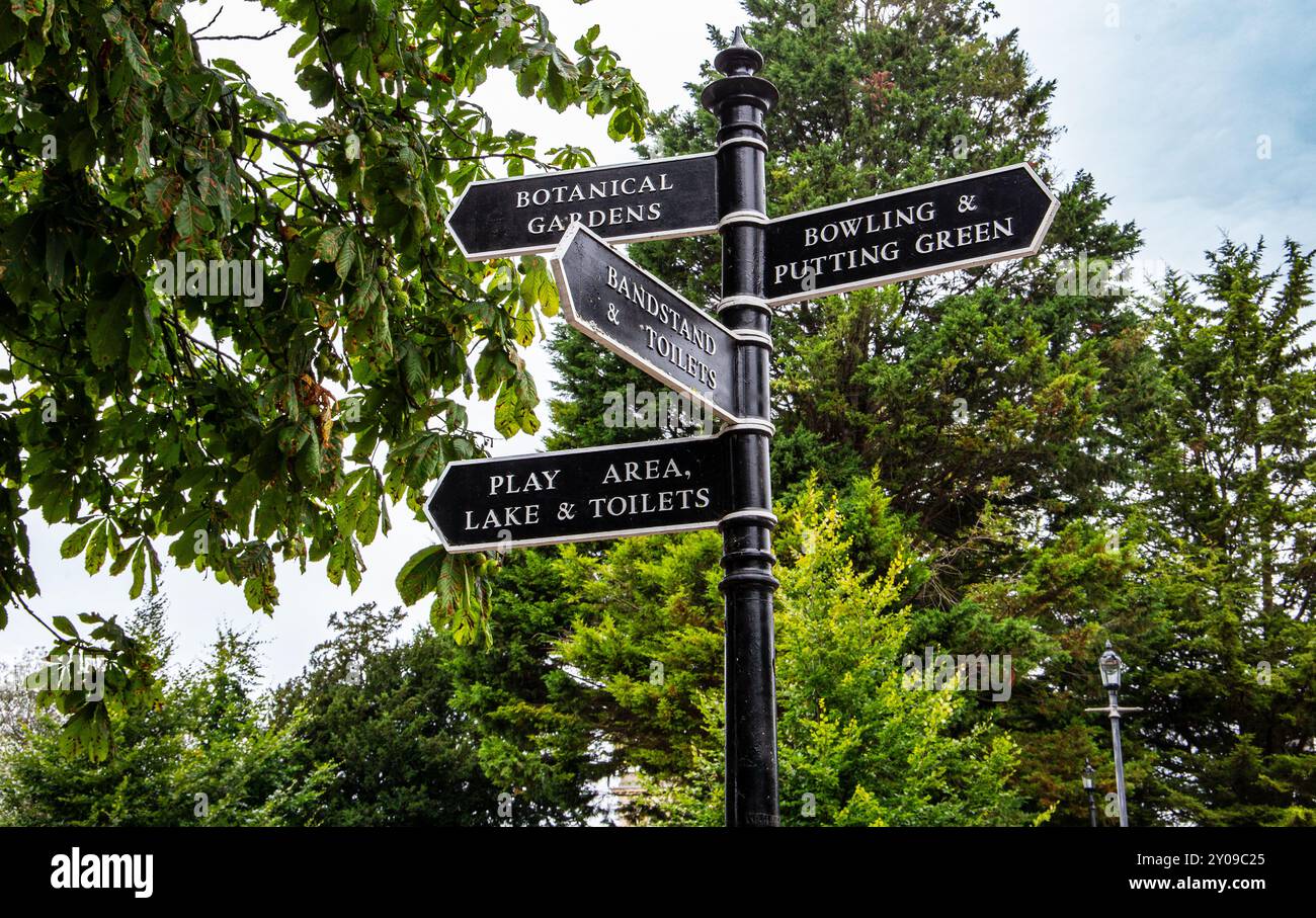 Un cartello direzionale in un parco che indica varie attrazioni tra cui giardini botanici, bowling e putting green, area giochi, lago e servizi igienici. Foto Stock