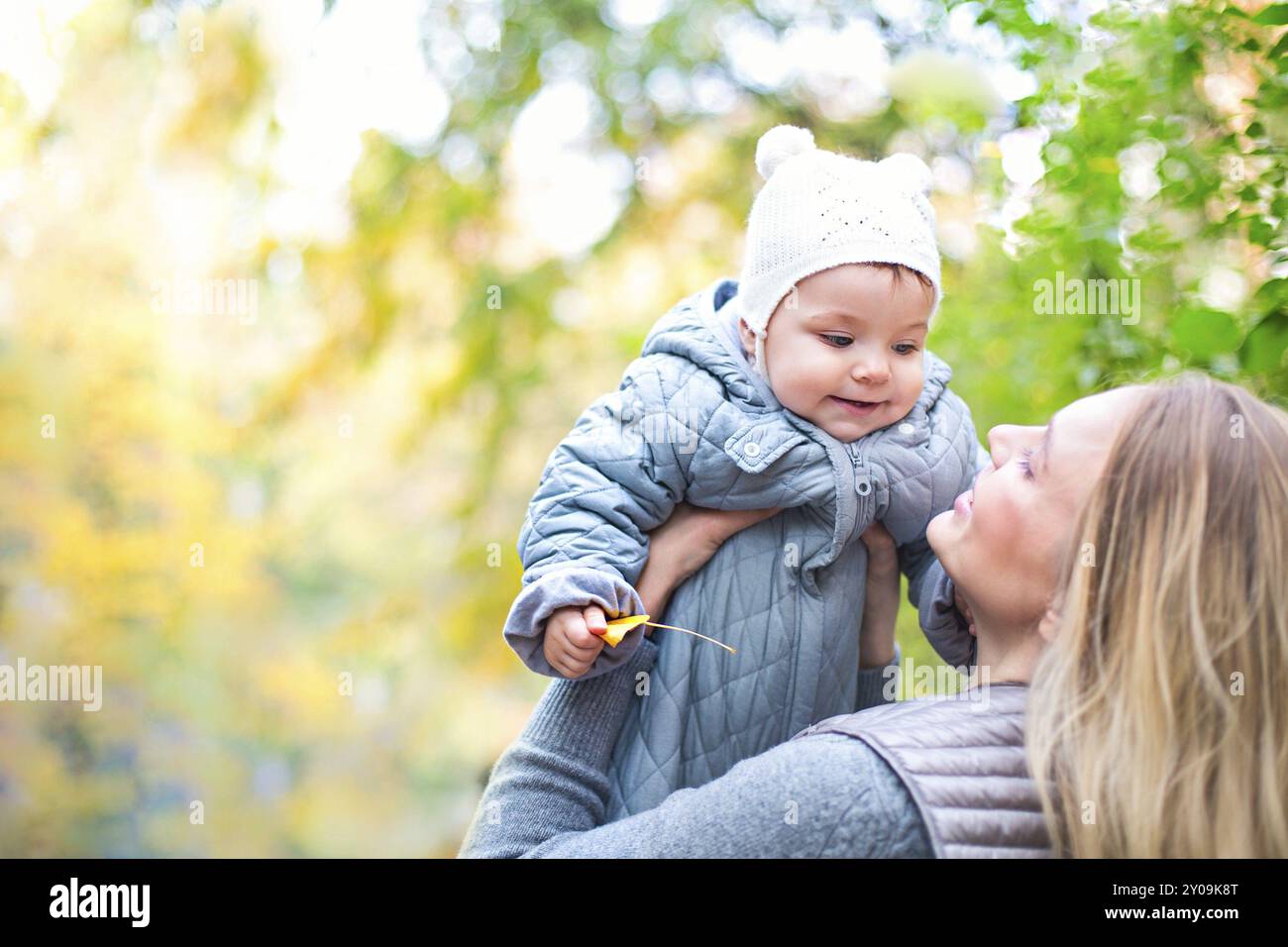 La famiglia felice all'esterno. Sua madre e la sua piccola figlia gioca cuddling in autunno a piedi nella natura all'aperto Foto Stock