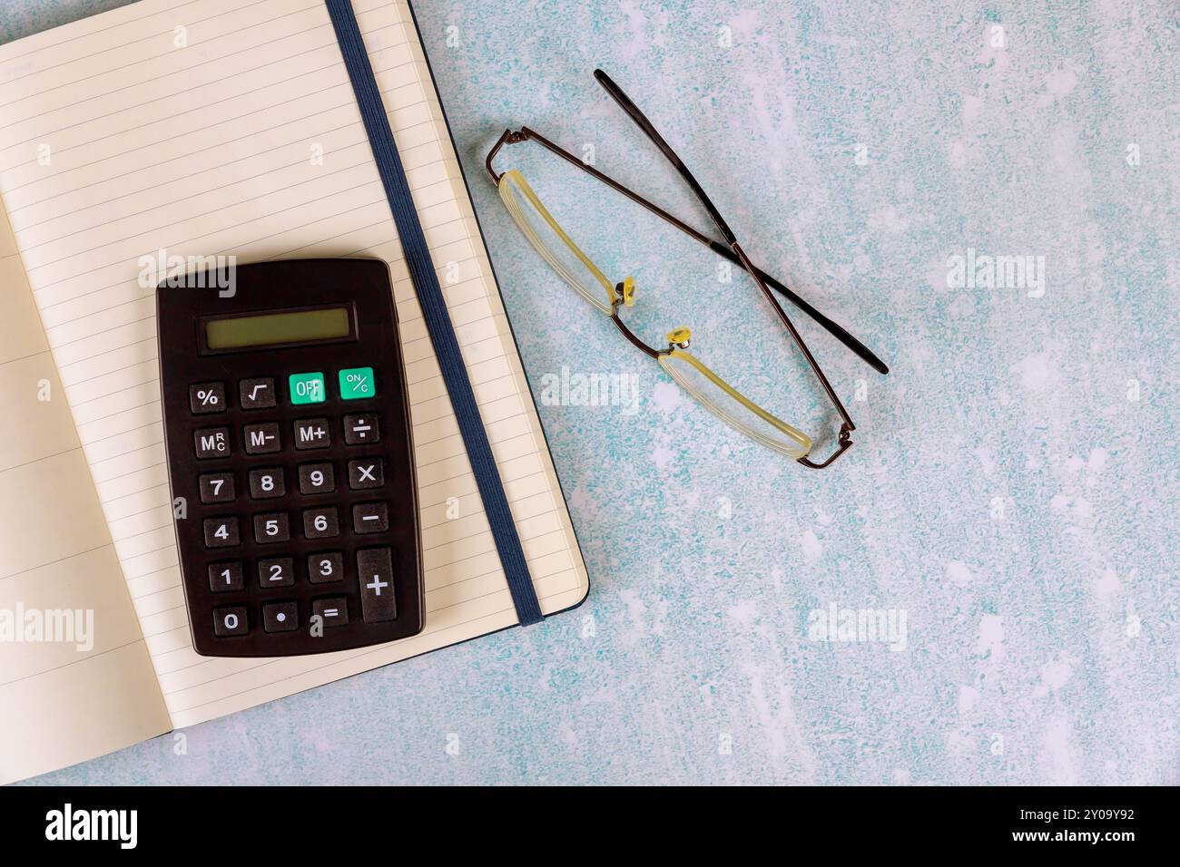 Sul moderno tavolo da ufficio ci sono notebook, occhiali, calcolatrice. Foto Stock