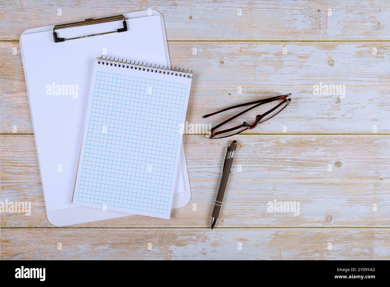 Negli uffici moderni, il notebook, gli occhiali e la penna possono essere visti sul tavolo per lavoro Foto Stock