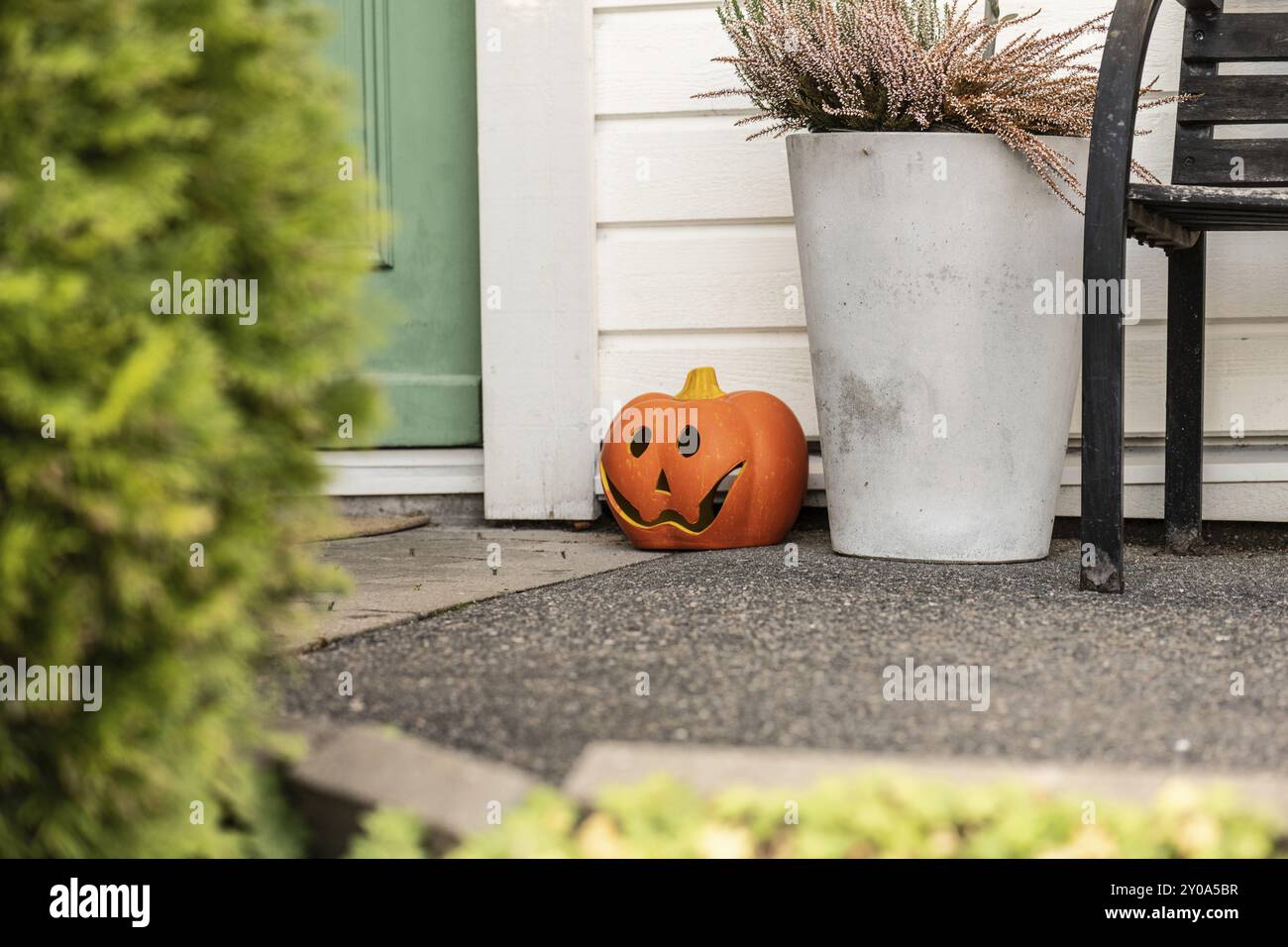 Zucca in plastica intagliata posta dai gradini di una porta verde Foto Stock