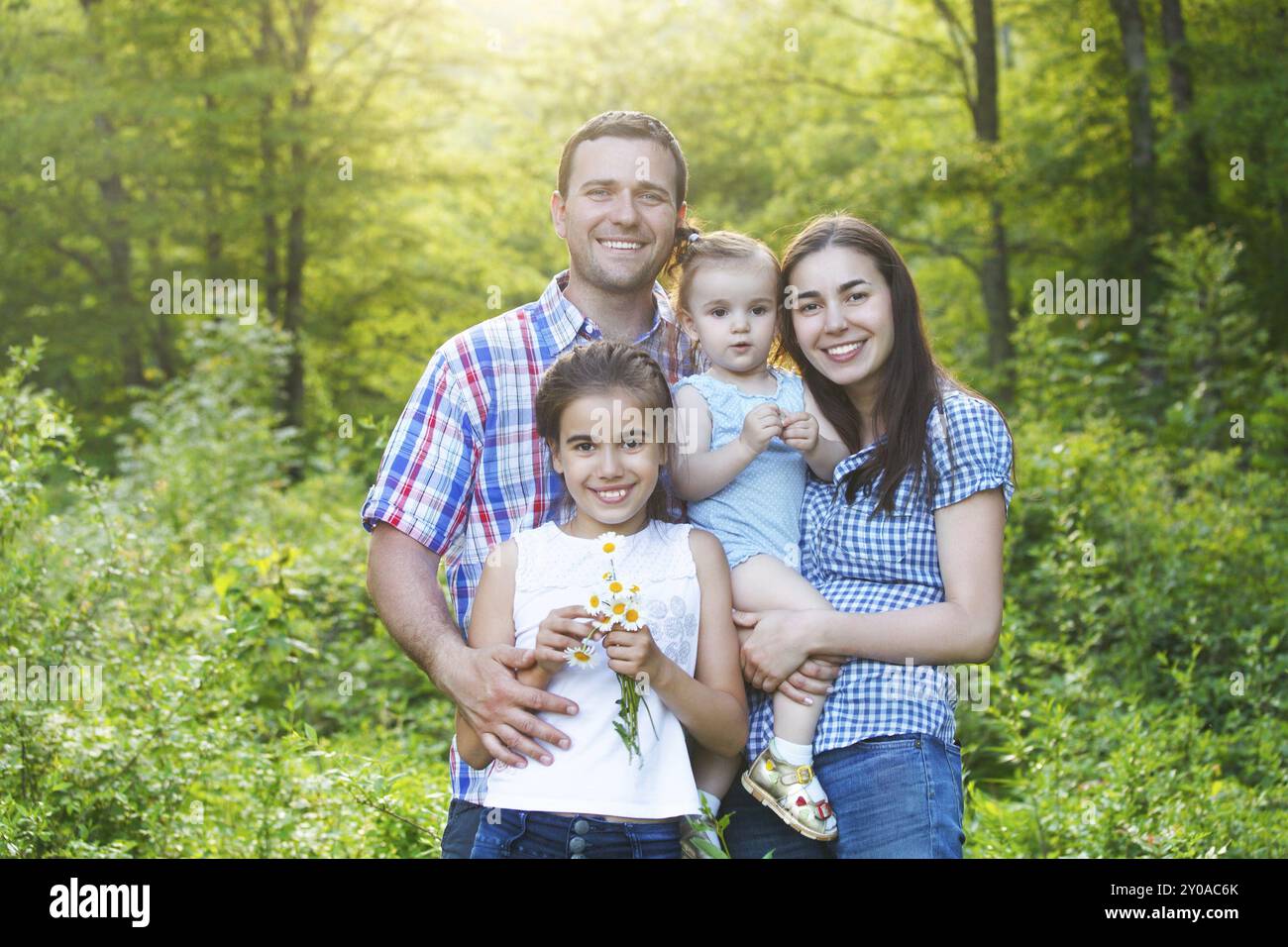 Felice giovane famiglia con due bambini nella foresta di primavera Foto Stock