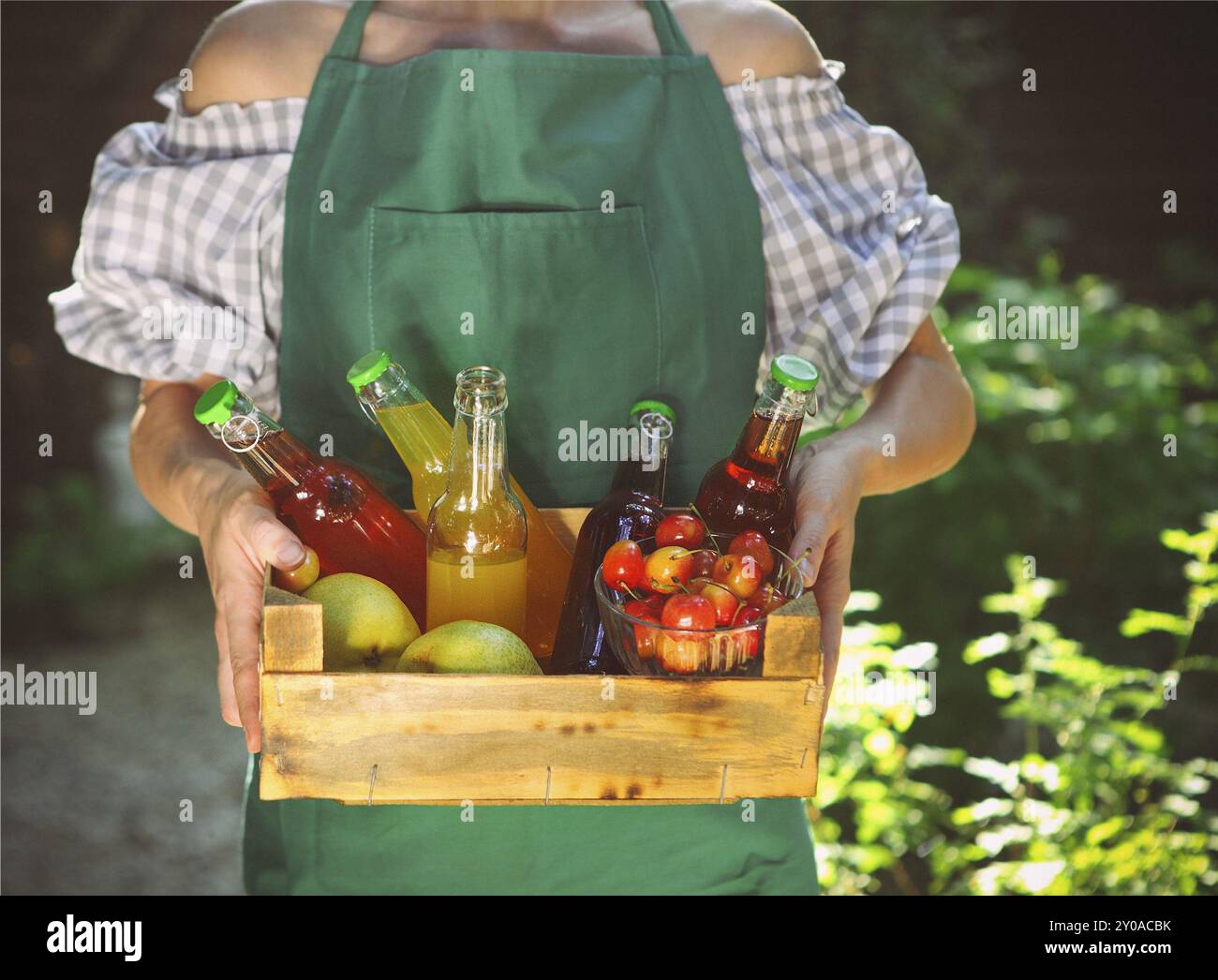 Donna che tiene in mano una scatola di legno con bottiglie di gusto limonata, ciliegia, pera e limone Foto Stock