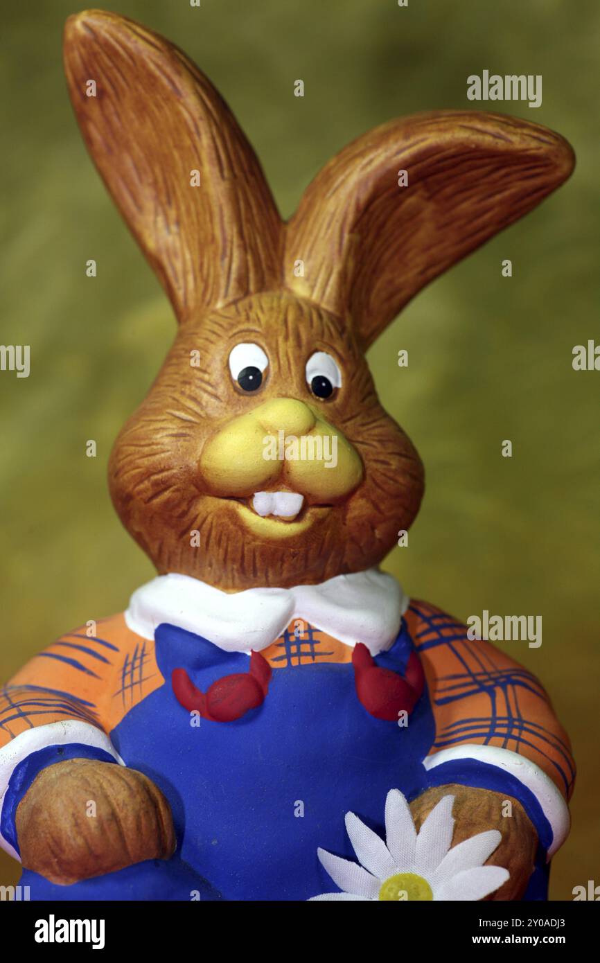 Divertente figura seduta di un coniglio con salopette blu Foto Stock