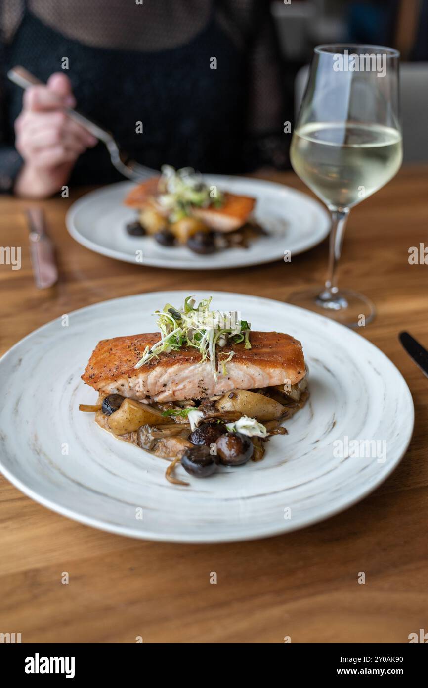Cena gourmet a base di pesce salmone con una donna in un ristorante romantico Foto Stock