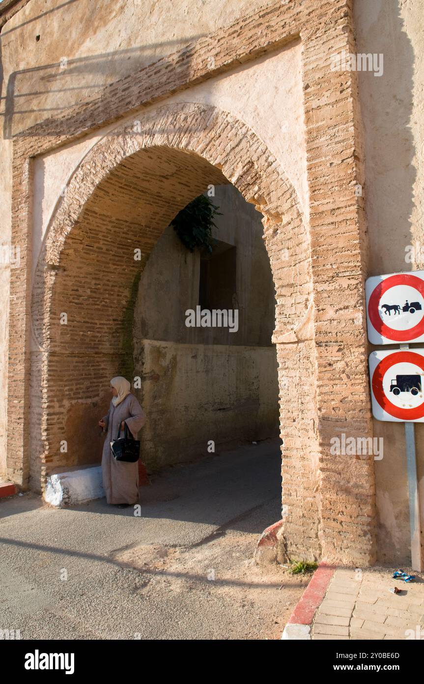 Una donna marocchina che cammina attraverso un cancello per la città vecchia di Meknes, in Marocco. Foto Stock