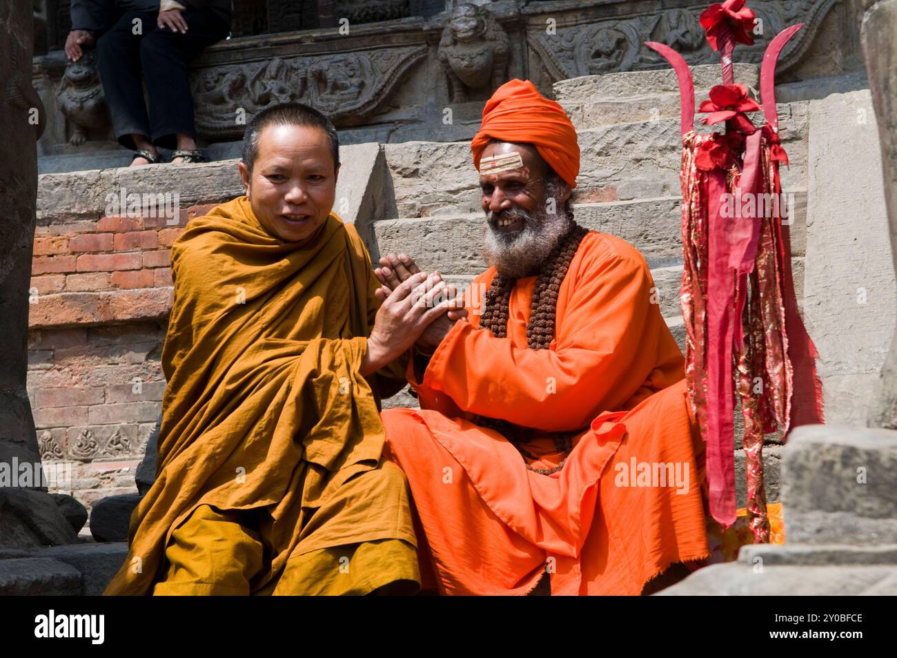 Un indù Sadhu e un monaco buddista si salutano a vicenda. Bhaktapur, Nepal. Foto Stock