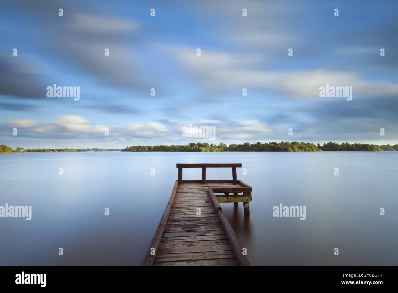 Molo in legno sul grande lago e cielo sfocato a causa della lunga esposizione Foto Stock