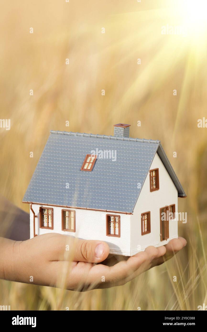 Casa nelle mani dei bambini su sfondo giallo autunnale. Concetto immobiliare Foto Stock