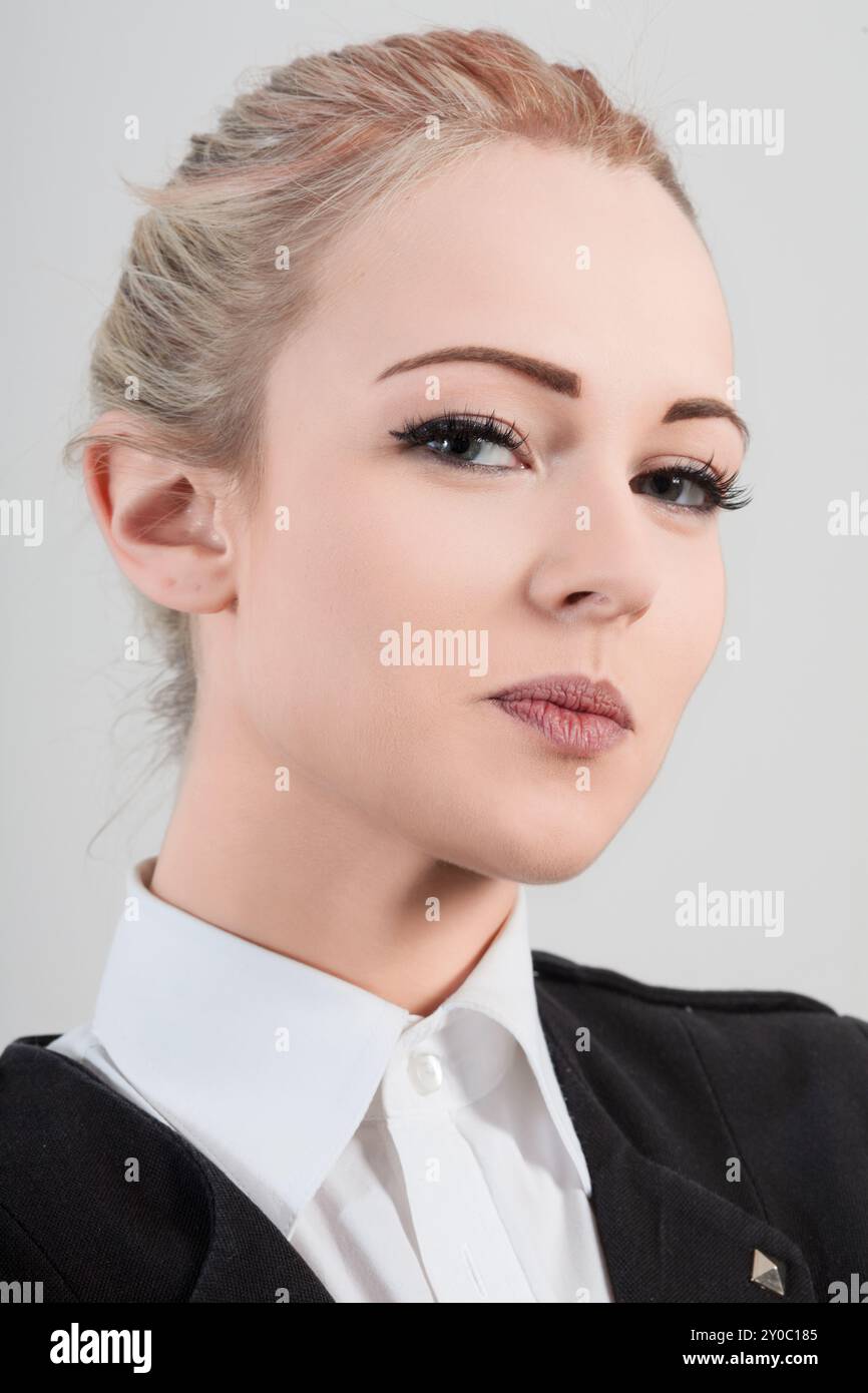 Giovane donna d'affari sicura di sé con camicia bianca e giacca nera trasuda professionalità e successo in un ambiente ufficio Foto Stock