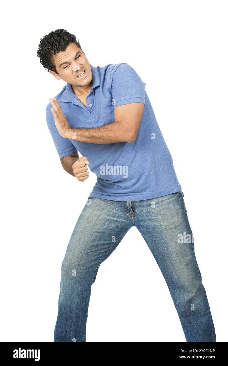 Un latinoamericano in lotta con jeans blu e camicia difendendo, forzando, spingendo, appoggiandosi alla spalla e a pieno peso contro un immaginario inserito h Foto Stock