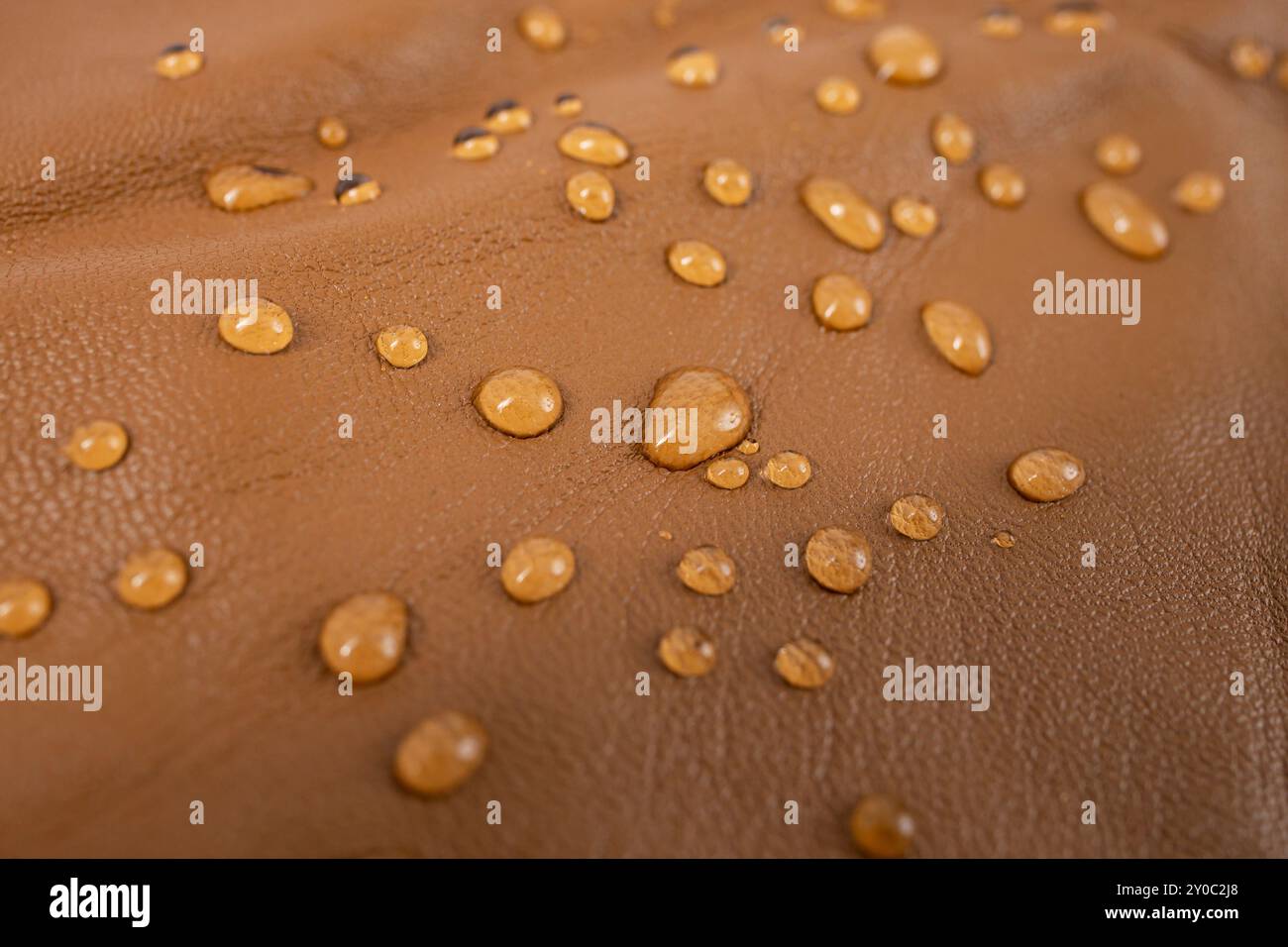 Gocce d'acqua rotonde sulla texture in pelle marrone beige, vista dall'alto, messa a fuoco ravvicinata morbida Foto Stock