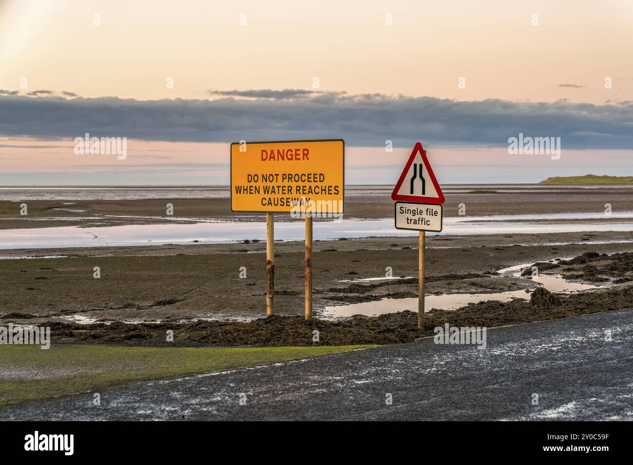 Segno: Singolo File traffico, Pericolo non procedere quando l'acqua raggiunge la Causeway, visto sulla strada tra Beal e Isola Santa in Northumberland, Inghilterra Foto Stock