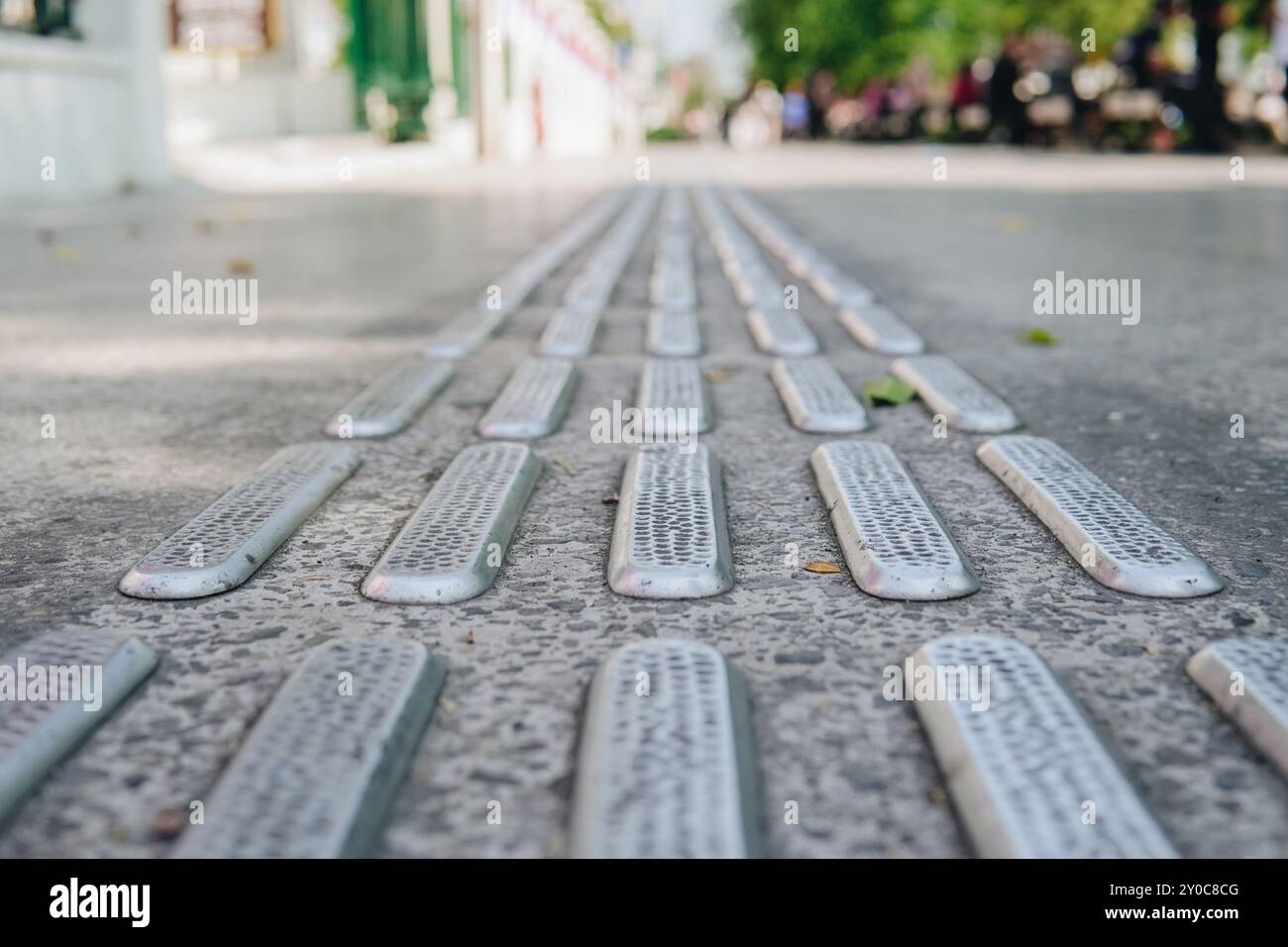 Primo piano di un marciapiede con una serie di piccole piastre metalliche. Le spranghe sono distanziate e sembrano far parte di una barriera del marciapiede. Concetto di cautela Foto Stock