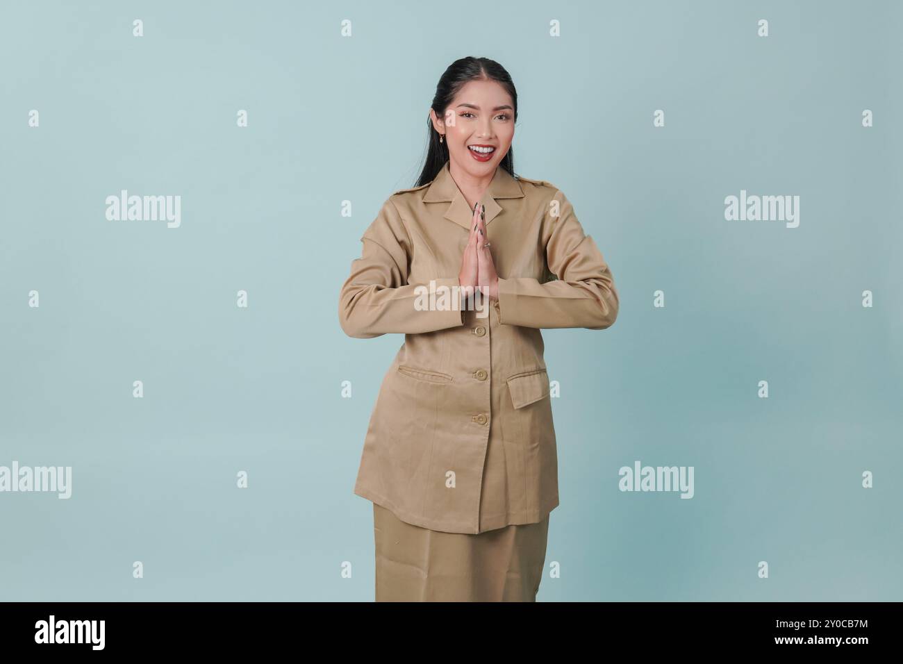 Un giovane impiegato del governo indonesiano che fa un gesto di saluto mentre sorride alla macchina fotografica. PNS e concetto di funzionario pubblico. Foto Stock