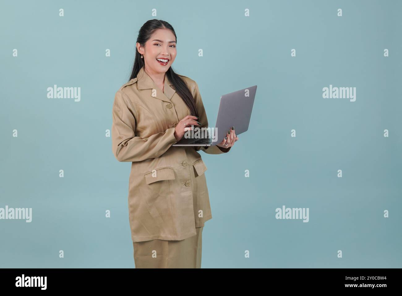 Felice lavoratrice del governo indonesiano che tiene il suo laptop e sorride alla fotocamera. Concetto di funzionario pubblico PNS. Foto Stock
