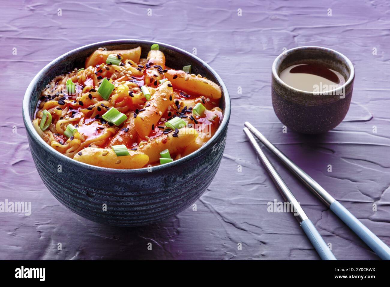 Rabokki, tteokbokki o topokki con ramen, cibo di strada coreano, torte di riso piccanti in salsa gochujang al pepe rosso, con bacchette e una bevanda, foto del cibo Foto Stock