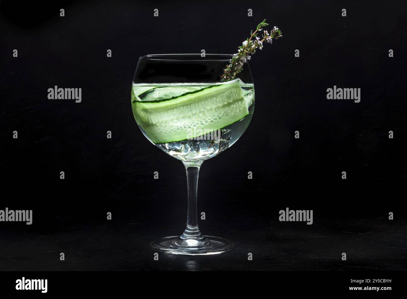 Fantastico cocktail fresco. Gin e bevanda tonica con ghiaccio a una festa, su sfondo nero. Alcol con cetriolo e timo Foto Stock