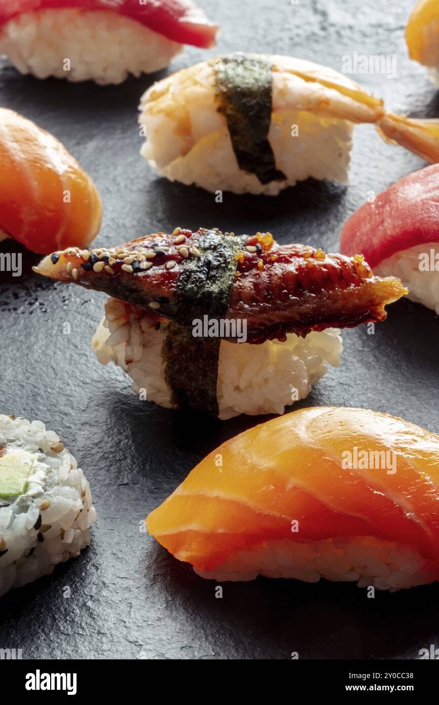 Sushi. Nigiri con anguilla, salmone e gamberi su sfondo nero, cibo giapponese su un piatto in un ristorante asiatico, fotografia gastronomica Foto Stock
