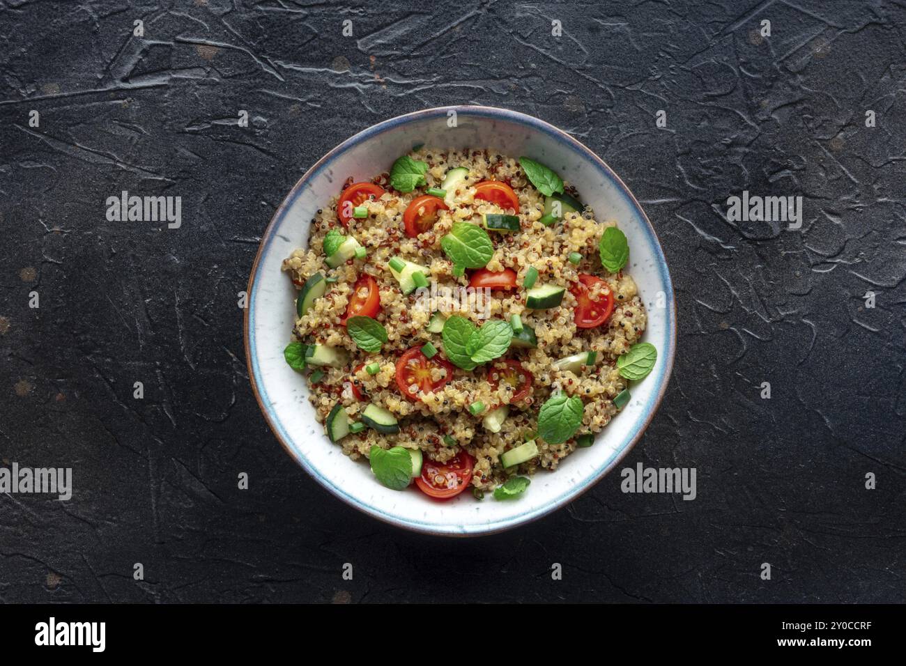 Insalata di tabbouleh di quinoa in una ciotola, una cena sana con pomodori e menta, foto dall'alto su sfondo di ardesia nera, fotografia di cibo, fotograp di cibo Foto Stock