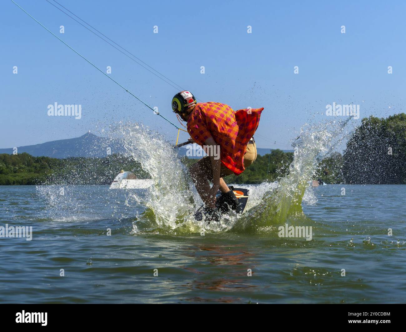 Giovane uomo casual con camicia battente sul wakeboard che salta nel lago, sci d'acqua e wakepark, Stras pod Ralskem, Repubblica Ceca, Europa Foto Stock
