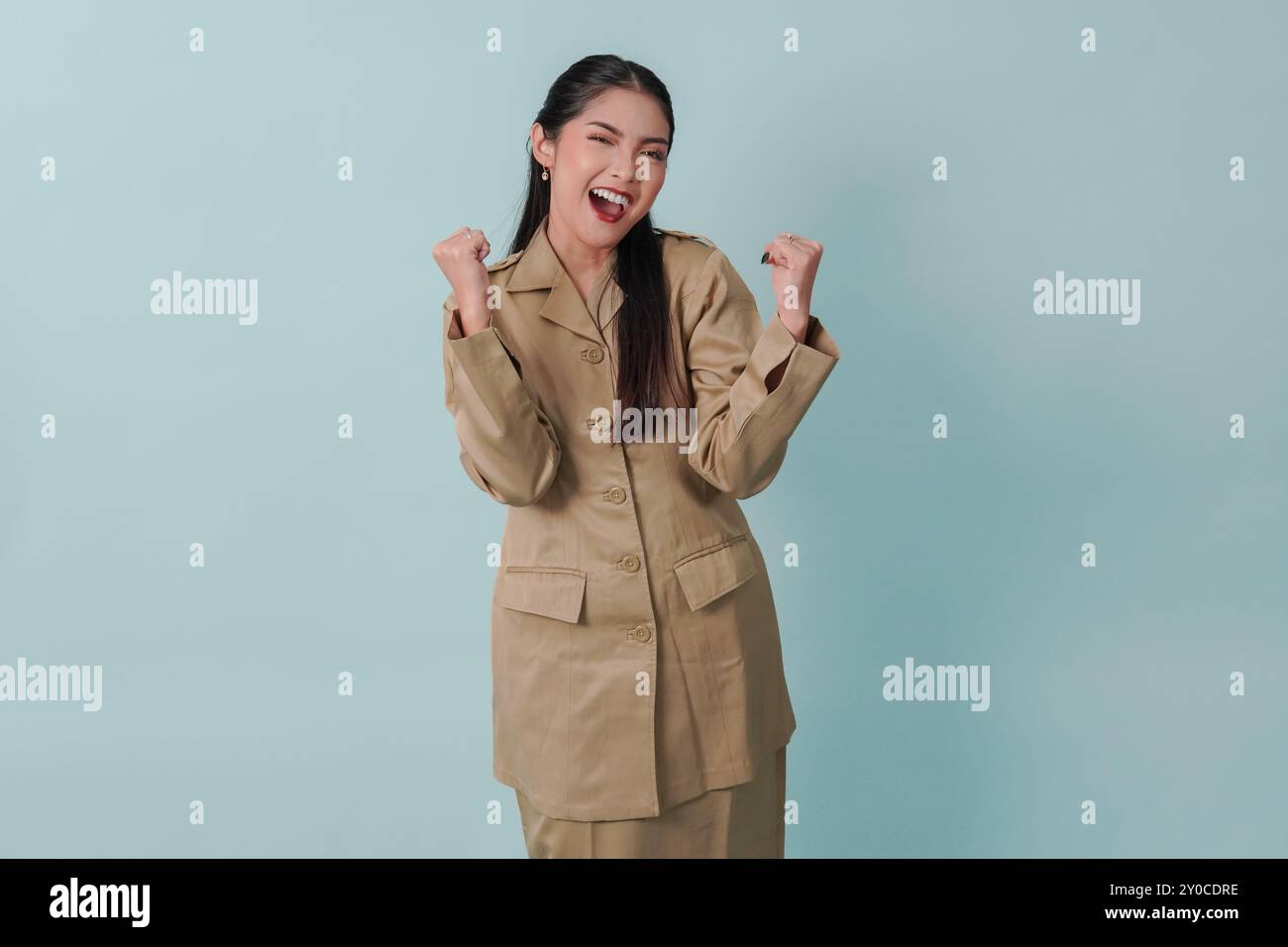Eccitata donna indonesiana lavoratrice del governo che indossa l'uniforme cachi in posa con una felice espressione di successo. Concetto di funzionario pubblico PNS. Foto Stock