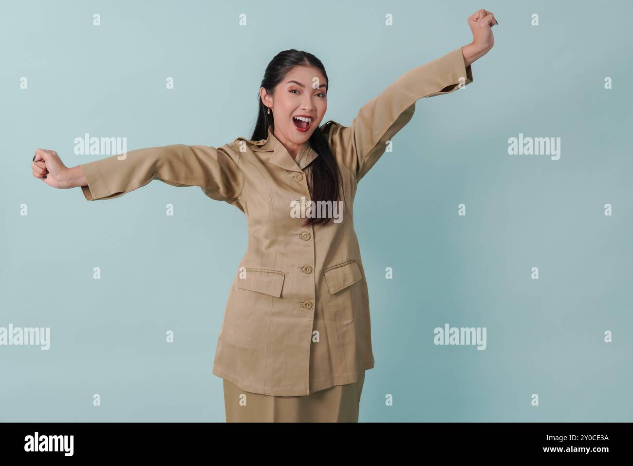 Eccitata donna indonesiana lavoratrice del governo che indossa l'uniforme cachi in posa con una felice espressione di successo. Concetto di funzionario pubblico PNS. Foto Stock