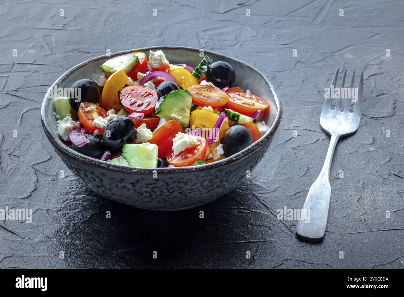 Insalata greca. Pomodoro e cetriolo freschi, peperone e formaggio Feta, cipolla e olive, con forchetta. Cibo estivo biologico, dieta sana, fotograp alimentare Foto Stock