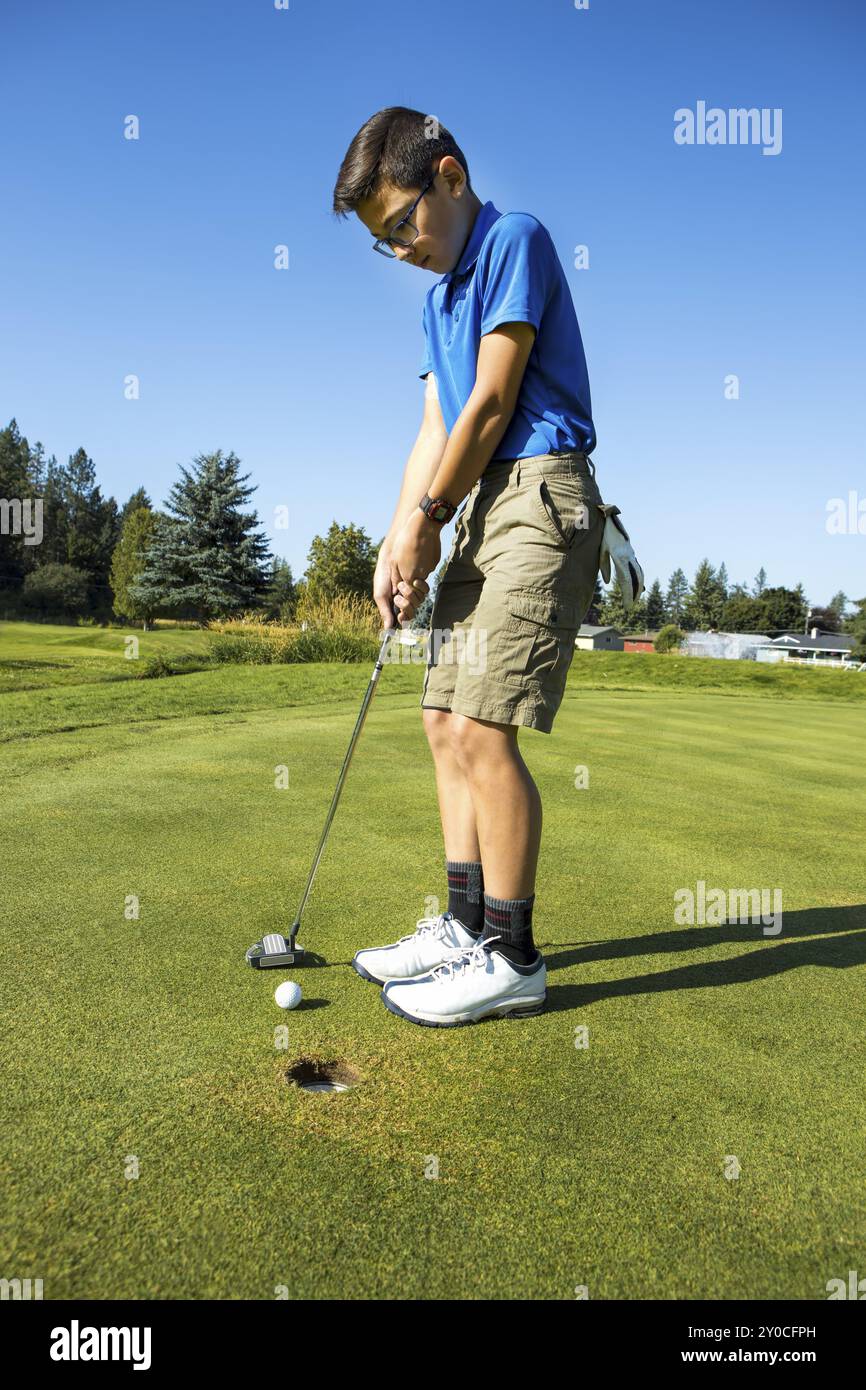 Un bambino più grande fa una breve putt in una giornata luminosa e soleggiata a Coeur d'Alene, Idaho Foto Stock