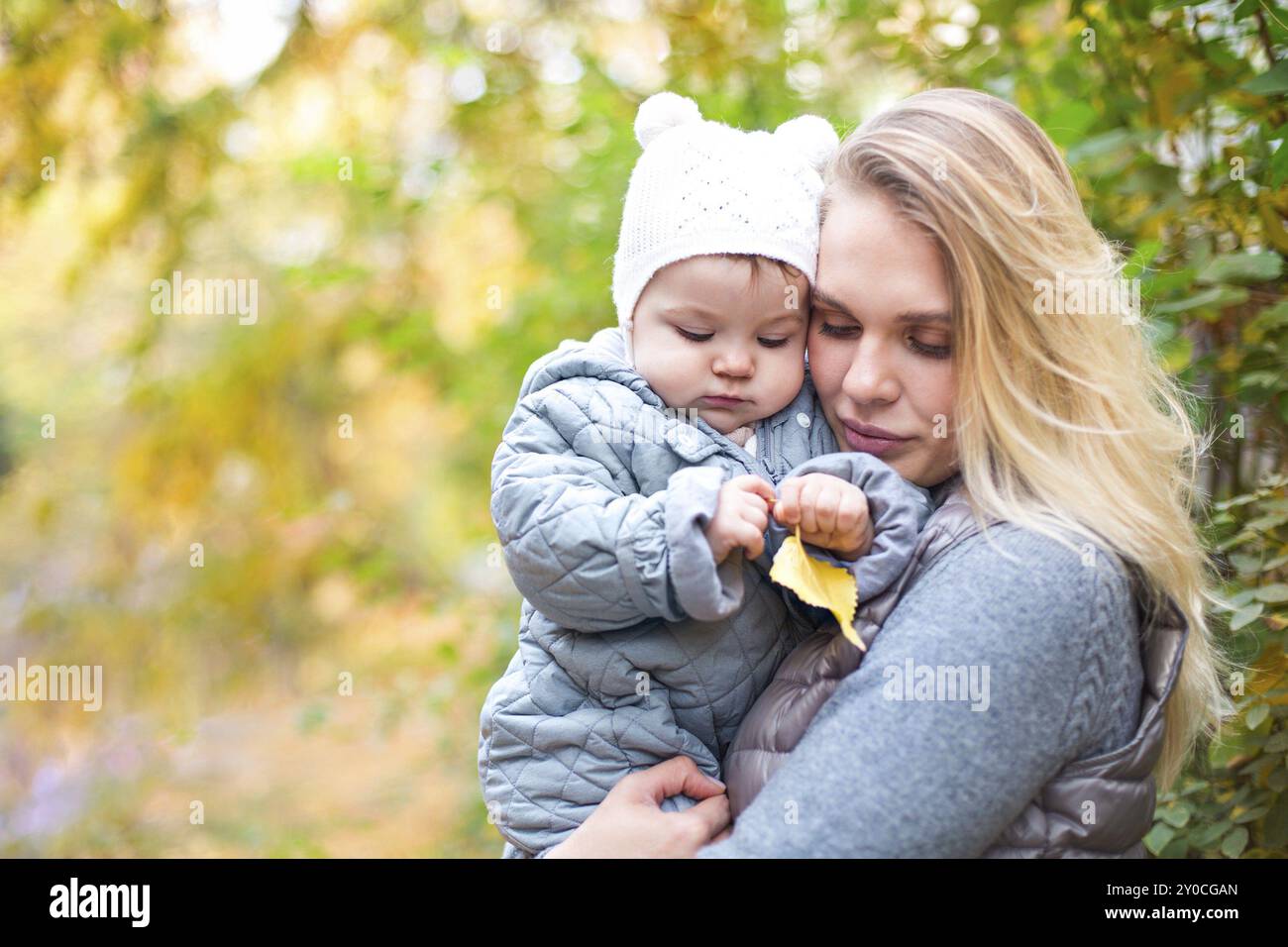 La famiglia felice all'esterno. Sua madre e la sua piccola figlia gioca cuddling in autunno a piedi nella natura all'aperto Foto Stock