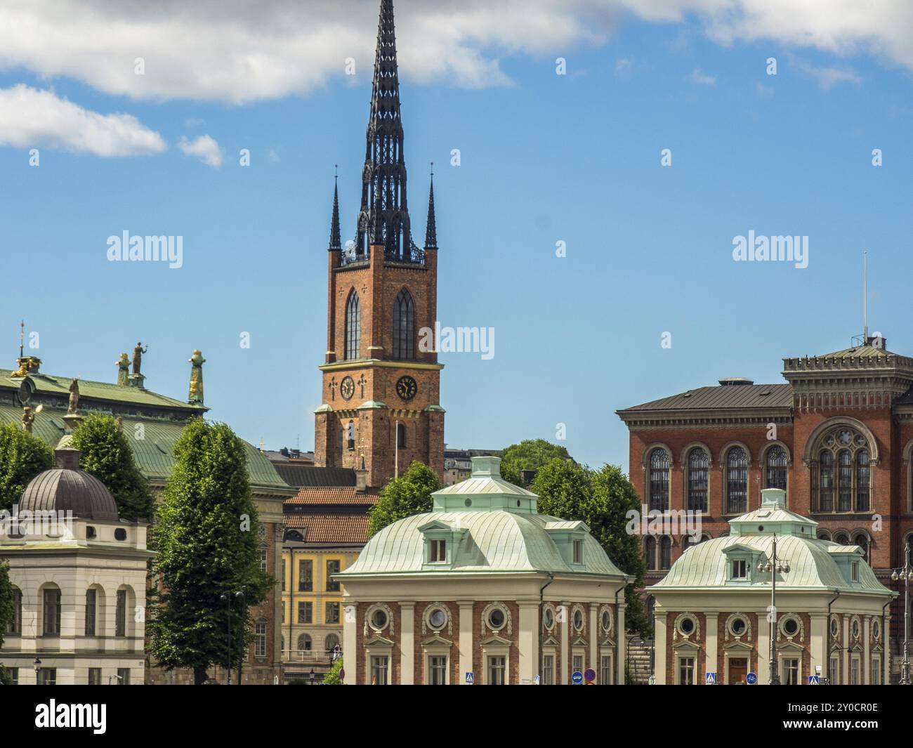 Immagine di imponenti edifici e di un'alta torre di chiesa sotto un cielo blu con nuvole bianche, stoccolma, Mar baltico, svezia, scandinavia Foto Stock