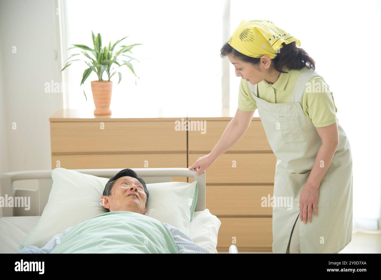 Un anziano a letto e un assistente Foto Stock