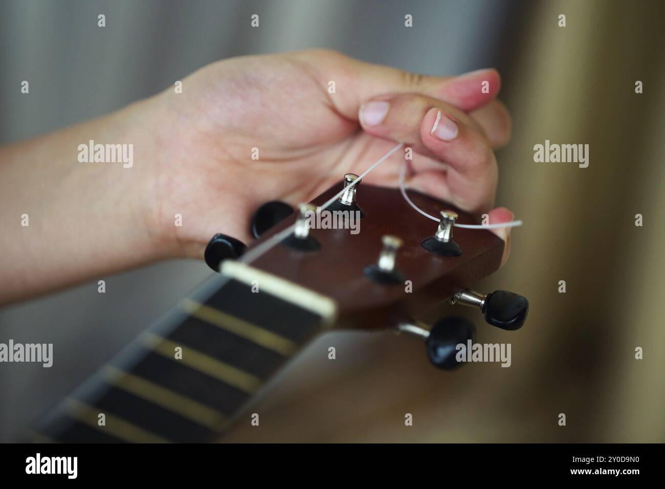 Tuning la stringa di ukulele, mani umane, primo piano. Processo di modifica della stringa di ukulele Foto Stock Tuning la stringa di ukulele, mani umane, primo piano. Processo di modifica della stringa di ukulele Foto Stock