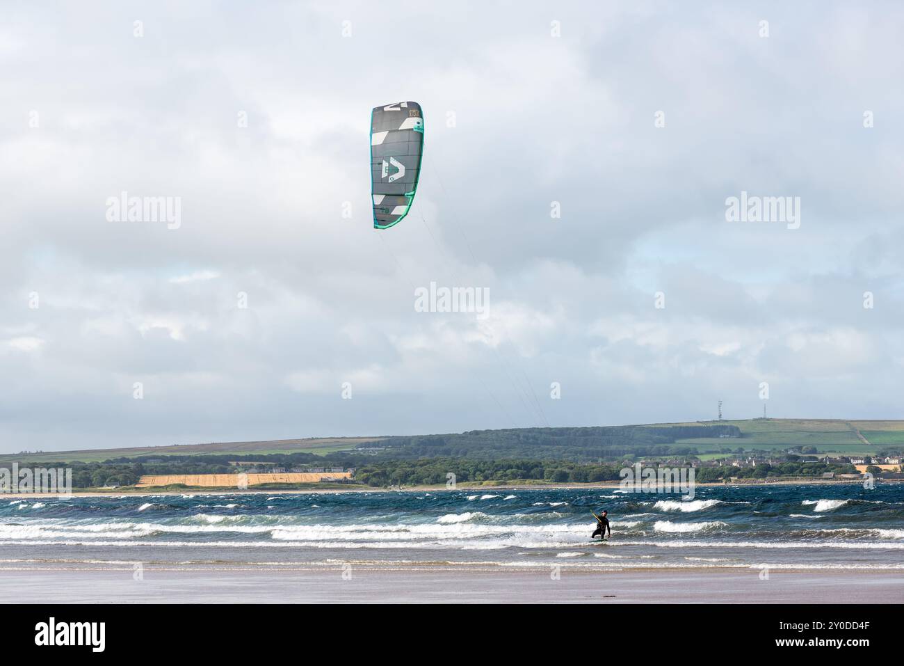 Dunnet, Scozia, Regno Unito - 30 agosto 2024: Uomo di kite surf con un aquilone nel cielo a bordo in mare cavalcando le onde a Dunnet Bay, uno dei più belli della Scozia Foto Stock